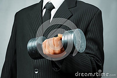 Strong businessman with metal dumbbell