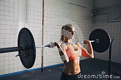 Strong woman lifting weights in crossfit gym