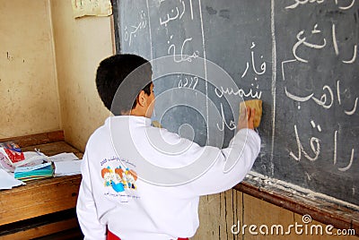 Student boy in classroom writing on blackboard