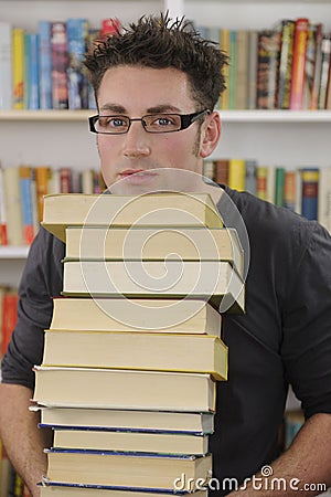 Student carrying stack of books in library