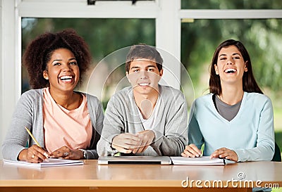 Student With Friends Sitting At Desk In Classroom