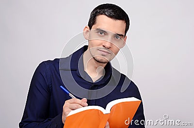 Student holding a book smiling. Teacher writing on a notebook.