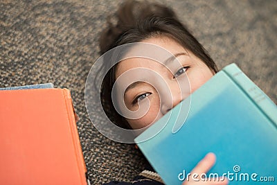 Student laying on carpet with books