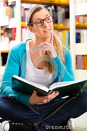 Student with pile of books learning in library