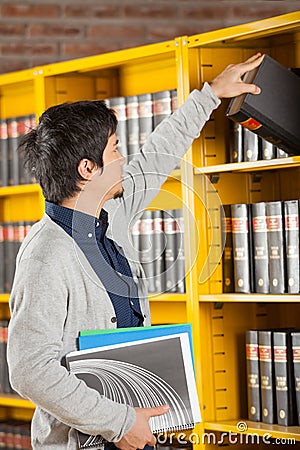 Student Taking Book From Shelf In University