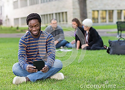 Student Using Digital Tablet On Grass At Campus