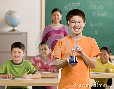 Student wearing goggles holds beaker of liquid