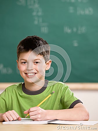 Student writing in notebook in school classroom