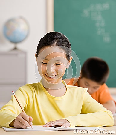 Student writing in notebook in school classroom