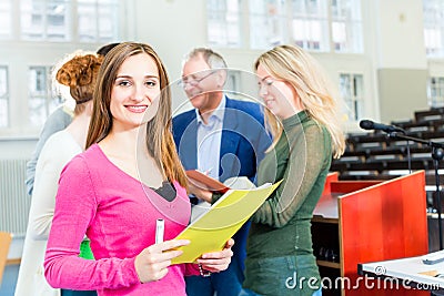 Students asking professor in college auditorium