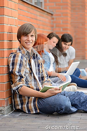 Studying boy friends sitting ground outside campus