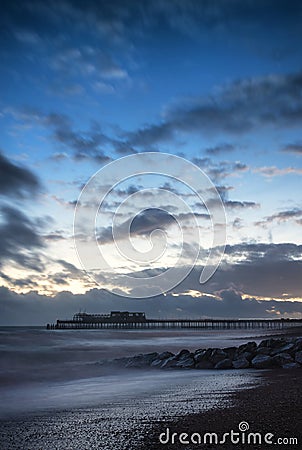 Stunning colorful Winter sunset sky above burned out pier at sea