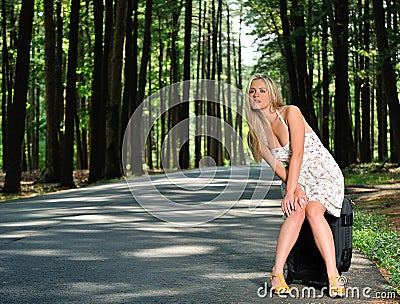 Stunning young blonde woman in sundress - waiting on road