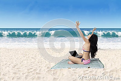 Successful woman working with laptop at beach