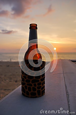 In a summer vacation. Bottle of beer on the beach at sunset