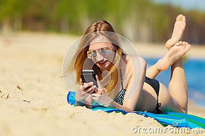 Summer vacation Girl with phone tanning on beach