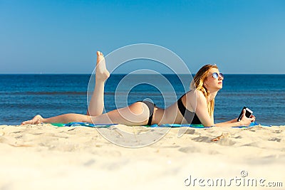 Summer vacation Girl with phone tanning on beach