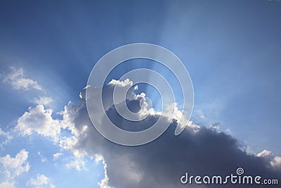 Sun beams behind cloud blue sky