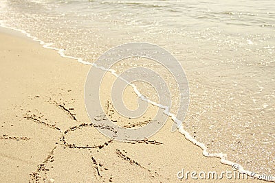 Sun drawn in the sand on the seashore