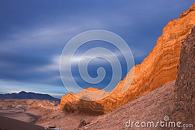 The sun is setting wonderfully on rocky cliffs in moon valley in the atacama desert while overcast by a stormy sky