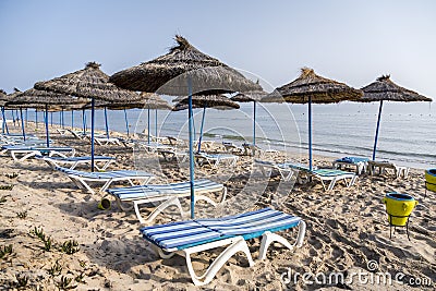 Sun umbrella on an empty beach and sea water horizon. Clear blue sky.