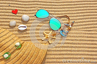 Sunglasses, Straw Hat and different objects on the beach sand