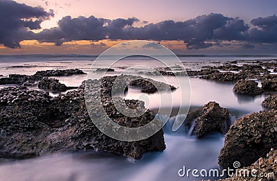 Sunrise landscape of ocean with waves clouds and rocks