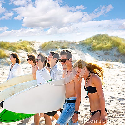 Surfer teen boys and girls group walking on beach