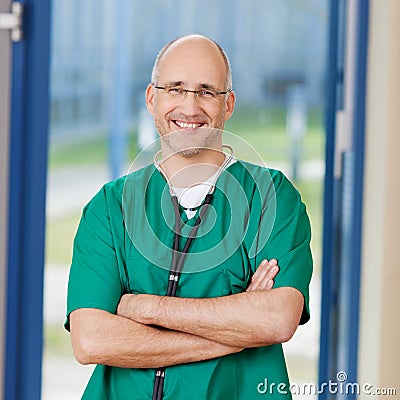 Surgeon In Scrubs Standing With Arms Crossed At Clinic