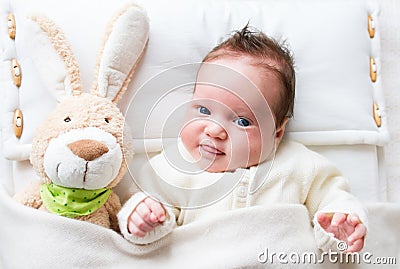 Sweet baby girl in a white crib with bunny toy