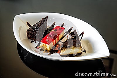 Sweet dessert of pieces of chocolate cakes and cheesecake with icing and fresh strawberry