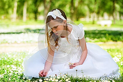Sweet girl in white dress picking flowers.