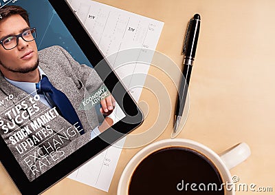 Tablet pc showing magazine on screen with a cup of coffee on a d