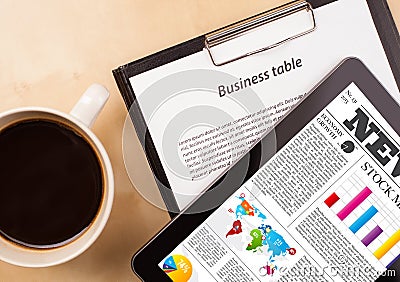 Tablet pc shows news on screen with a cup of coffee on a desk