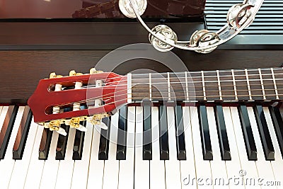 Tambourine and neck of guitar on piano keyboard.