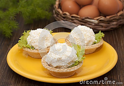 Tartlets with cheese and egg balls on a yellow plate and eggs in