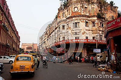 Taxi cab stopped in front of the old hotel on the busy street