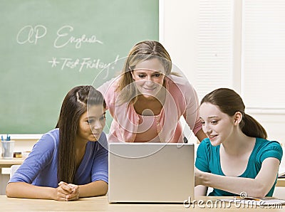 Teacher helping students on laptop