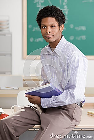 Teacher holding school book posing in classroom