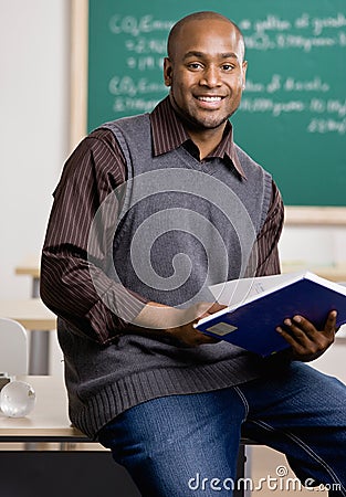 Teacher sitting on desk with text book