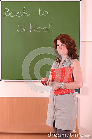 Teacher stand with book and apple in her hand