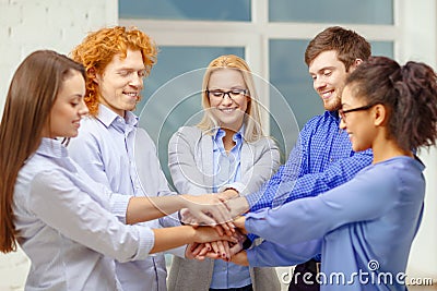 Team with hands on top of each other in office