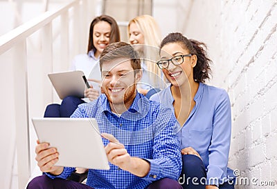 Team with tablet pc computer sitting on staircase