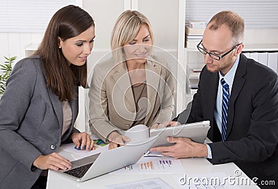 Team of three business people sitting together at desk in a meet