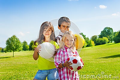 Team of three happy kids with balls