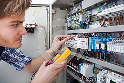 Technician examining fusebox with insulation resistance tester