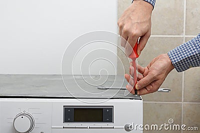 Technician fixing washing machine with screwdriver