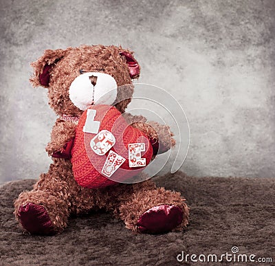 Teddy bear holds in paws heart symbol .