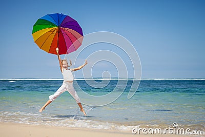 Teen girl jumping on the beach at blue sea shore in summer vaca