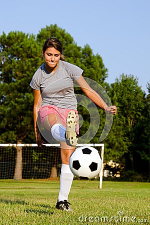 Teen girl kicking soccer ball